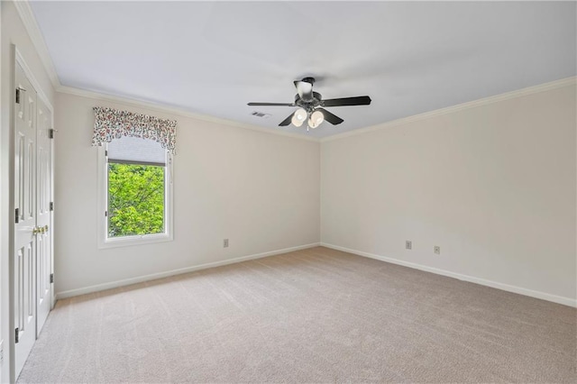 spare room with crown molding, baseboards, ceiling fan, and visible vents