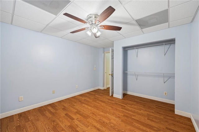 unfurnished bedroom featuring a ceiling fan, visible vents, wood finished floors, baseboards, and a drop ceiling