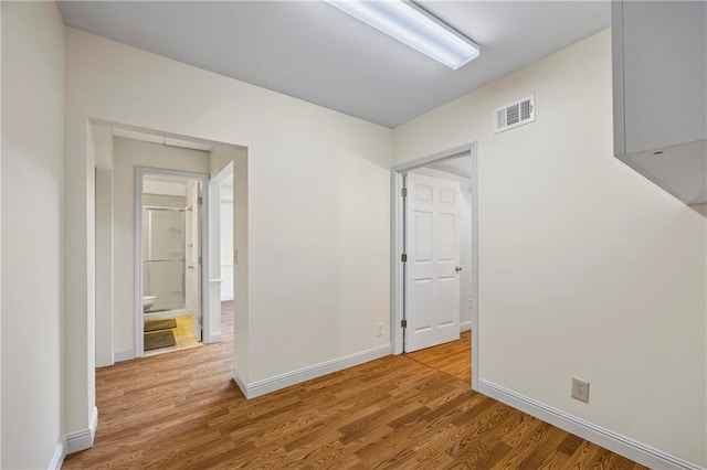 spare room featuring baseboards, wood finished floors, and visible vents