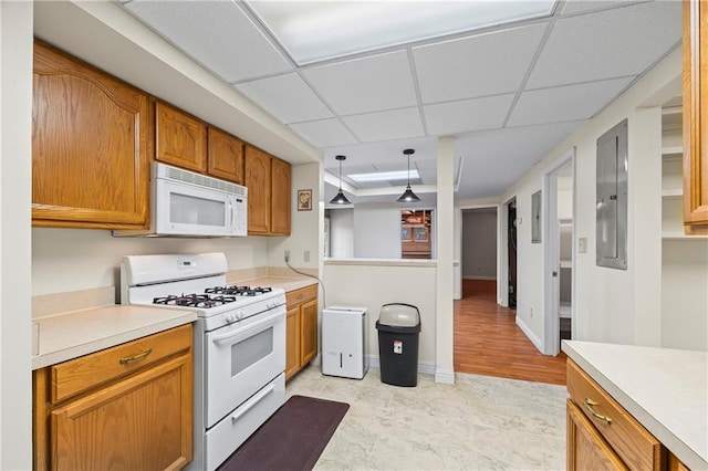 kitchen with pendant lighting, brown cabinets, light countertops, a drop ceiling, and white appliances