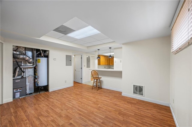 basement with visible vents, light wood-style flooring, water heater, and electric panel