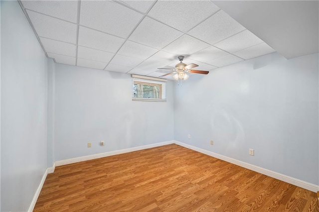 below grade area with baseboards, a paneled ceiling, and wood finished floors