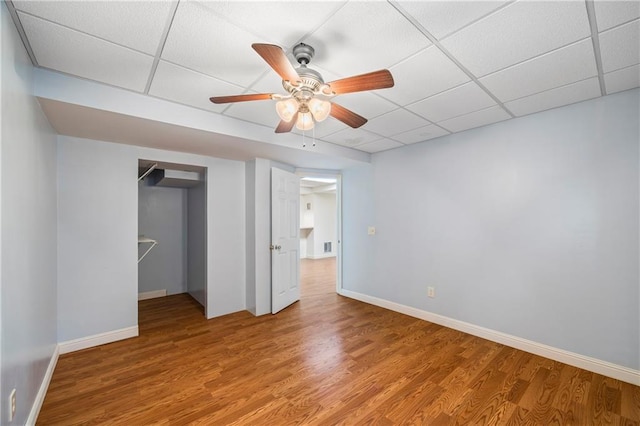 unfurnished bedroom featuring baseboards, a drop ceiling, and wood finished floors