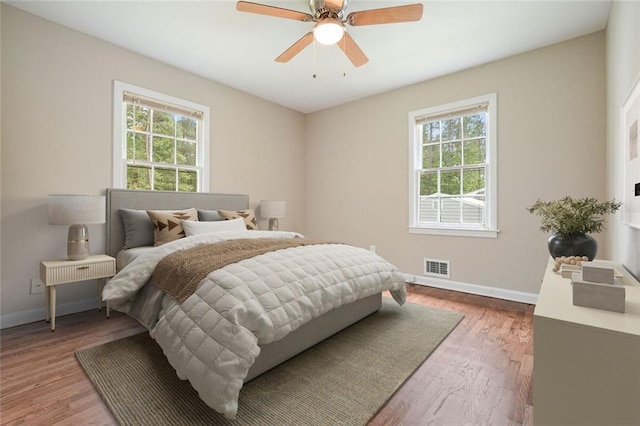 bedroom with multiple windows, baseboards, and wood finished floors