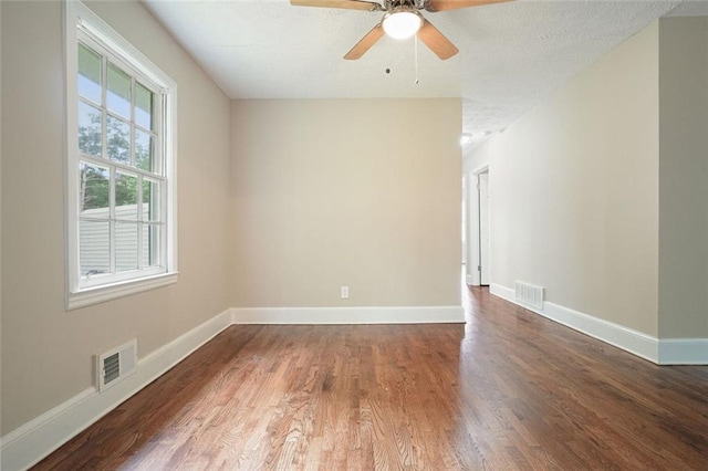 empty room featuring wood finished floors, baseboards, ceiling fan, and a textured ceiling