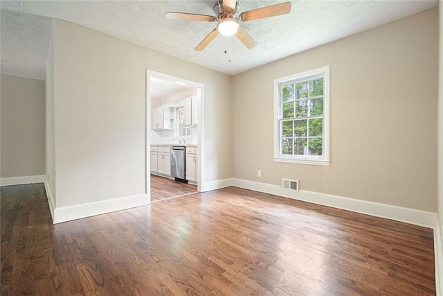empty room with wood finished floors, a textured ceiling, ceiling fan, and baseboards