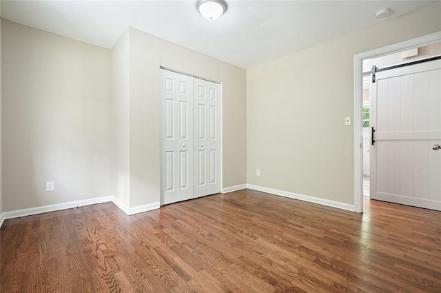 unfurnished bedroom featuring wood finished floors, baseboards, and a closet