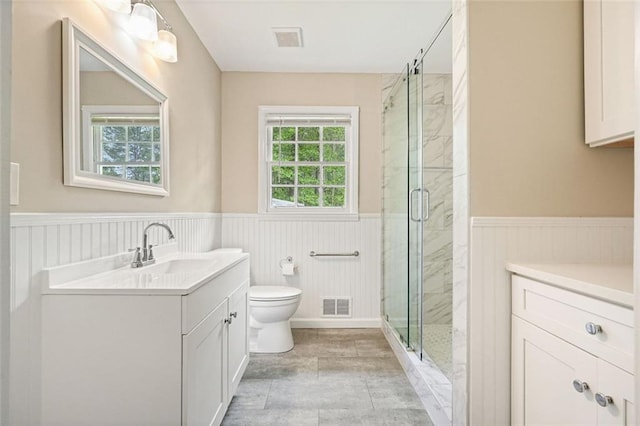 bathroom featuring toilet, wainscoting, vanity, and a marble finish shower