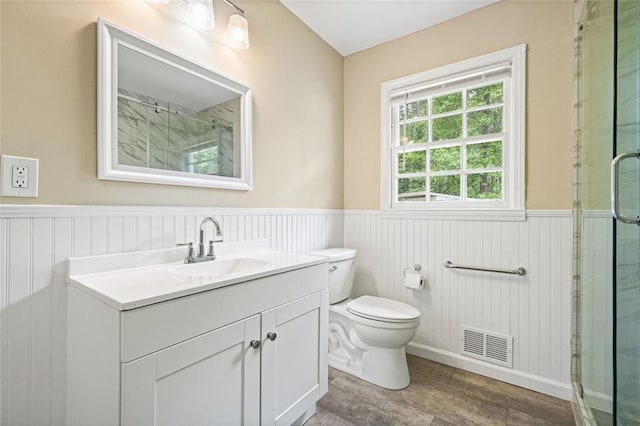 full bathroom with a wainscoted wall, a stall shower, vanity, toilet, and wood finished floors