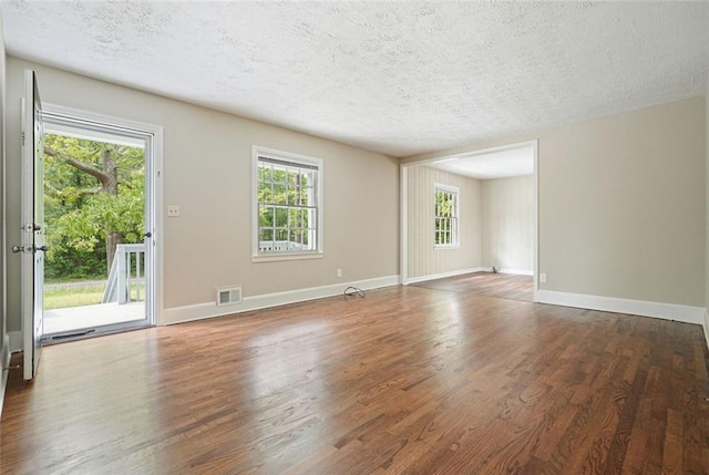 unfurnished room featuring wood finished floors, a textured ceiling, and baseboards