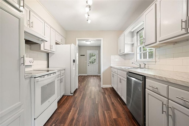 kitchen with white appliances, a sink, under cabinet range hood, dark wood-style floors, and light countertops
