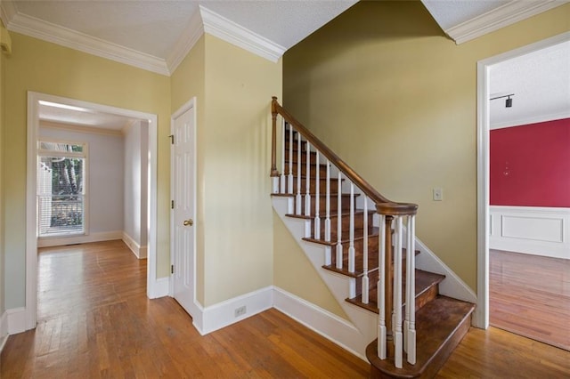 staircase featuring crown molding, a textured ceiling, and hardwood / wood-style flooring