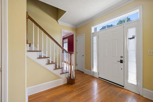 foyer entrance with a textured ceiling, crown molding, and wood-type flooring