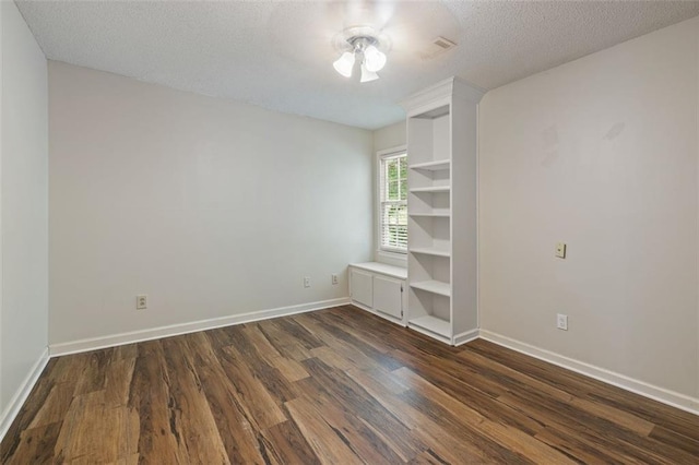 spare room with dark wood-type flooring, a textured ceiling, and ceiling fan