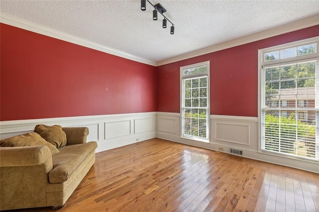 sitting room with light wood-type flooring, crown molding, track lighting, and a textured ceiling