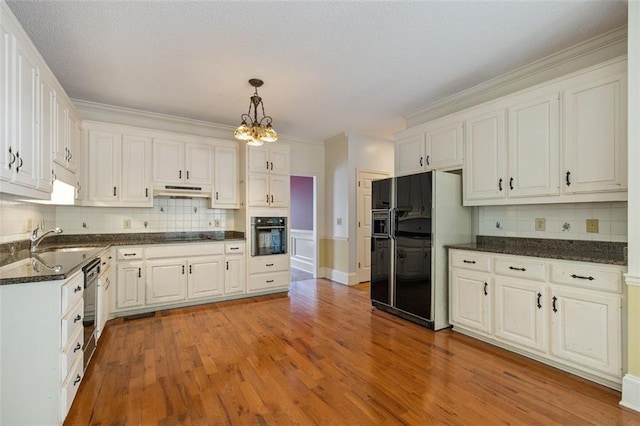 kitchen with black appliances, hanging light fixtures, hardwood / wood-style floors, and decorative backsplash