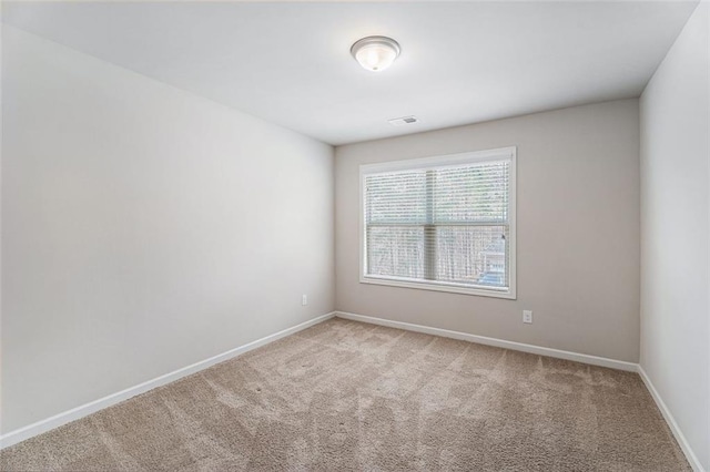 spare room featuring baseboards, visible vents, and light colored carpet