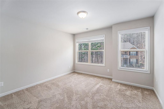 empty room featuring light colored carpet, visible vents, and baseboards