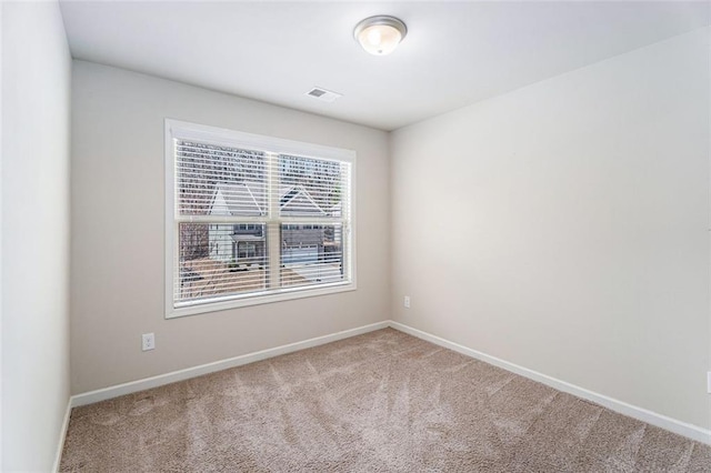 spare room featuring carpet, visible vents, and baseboards