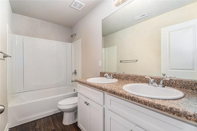 bathroom featuring toilet, wood finished floors, a sink, and visible vents