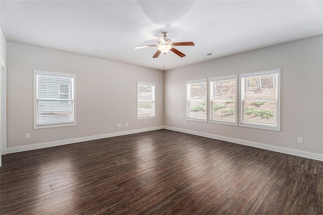 empty room with dark wood-style floors, baseboards, visible vents, and a ceiling fan