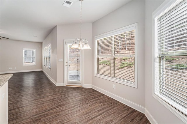 unfurnished dining area with a chandelier, dark wood-style flooring, visible vents, and baseboards