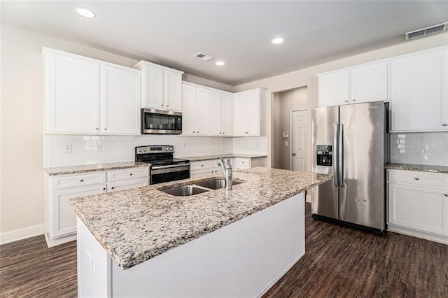 kitchen with visible vents, dark wood finished floors, light stone counters, stainless steel appliances, and a sink