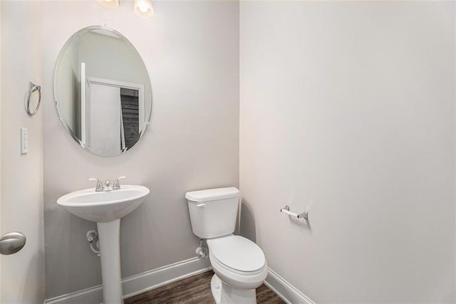 bathroom with toilet, a sink, baseboards, and wood finished floors