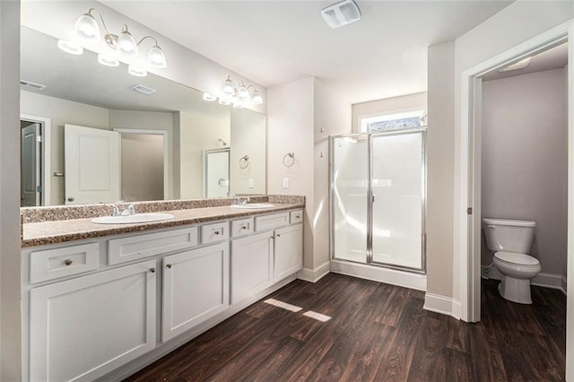 bathroom featuring visible vents, a sink, a shower stall, and wood finished floors