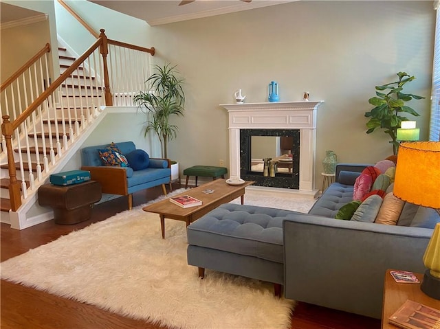 living room featuring ornamental molding, stairway, a premium fireplace, and wood finished floors