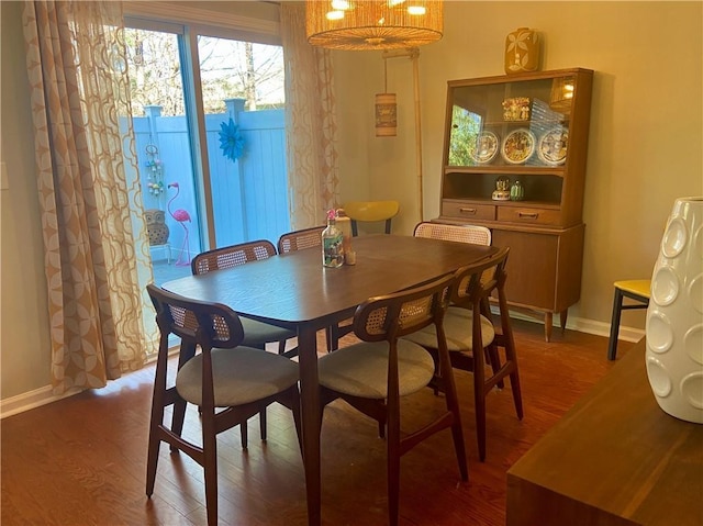 dining room featuring dark wood-style flooring, baseboards, and an inviting chandelier