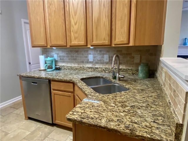 kitchen with light stone counters, a sink, baseboards, backsplash, and dishwasher