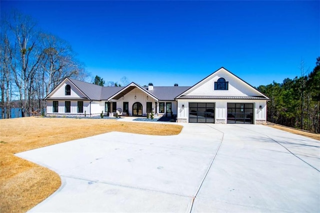 modern farmhouse style home with driveway, a garage, metal roof, a standing seam roof, and a front yard