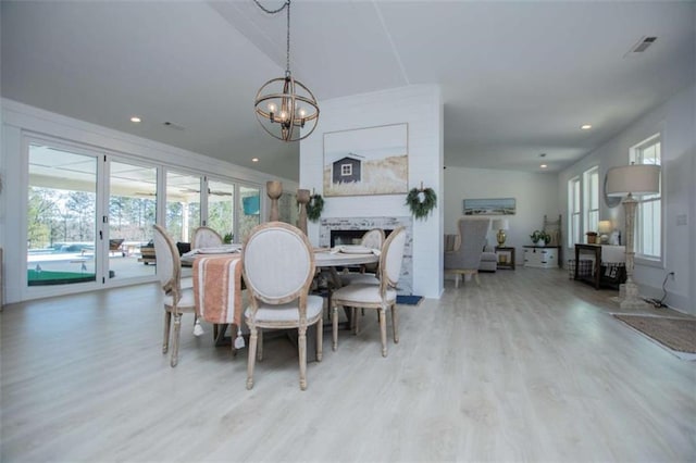 dining area featuring a chandelier, recessed lighting, a fireplace, and wood finished floors