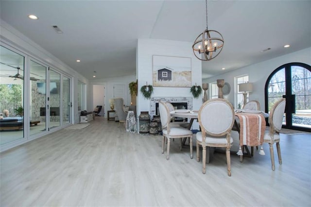 dining room with ceiling fan with notable chandelier, recessed lighting, a fireplace, and wood finished floors