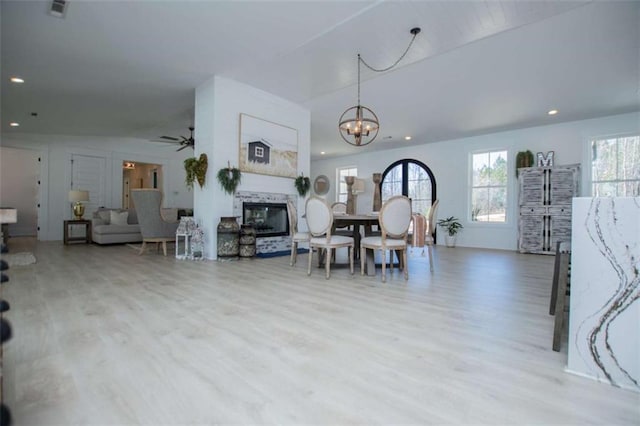 dining space featuring visible vents, a glass covered fireplace, wood finished floors, ceiling fan with notable chandelier, and recessed lighting