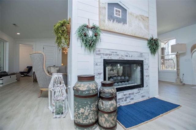 interior space with a glass covered fireplace and wood finished floors