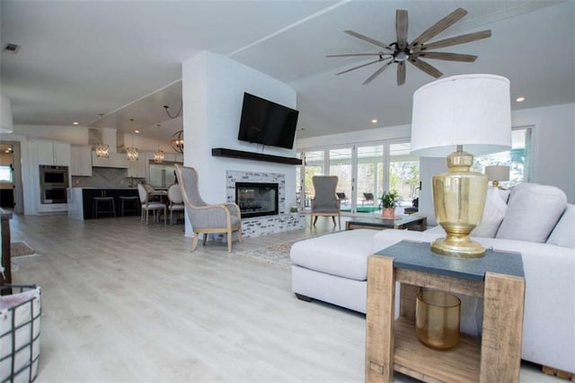 living room featuring visible vents, wood finished floors, vaulted ceiling, a fireplace, and recessed lighting