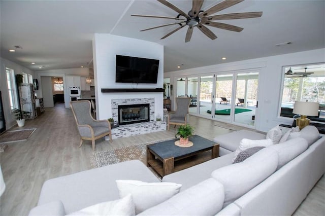 living room with lofted ceiling, recessed lighting, a ceiling fan, wood finished floors, and a tile fireplace