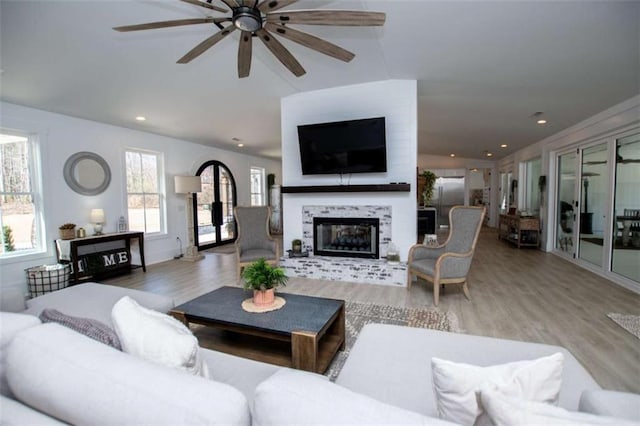 living room featuring ceiling fan, a tiled fireplace, wood finished floors, and recessed lighting