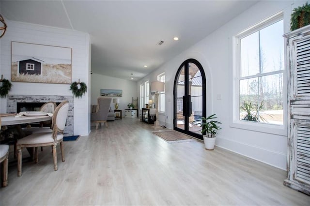 foyer with a healthy amount of sunlight, a fireplace, baseboards, and wood finished floors