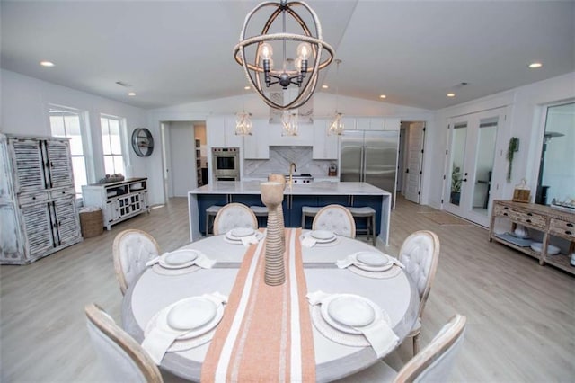 dining area with a chandelier, light wood-type flooring, vaulted ceiling, and recessed lighting