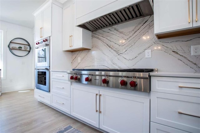 kitchen featuring stainless steel appliances, white cabinets, decorative backsplash, and custom exhaust hood