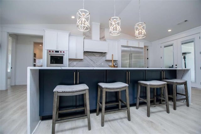 kitchen featuring lofted ceiling, built in fridge, white cabinetry, white oven, and decorative backsplash