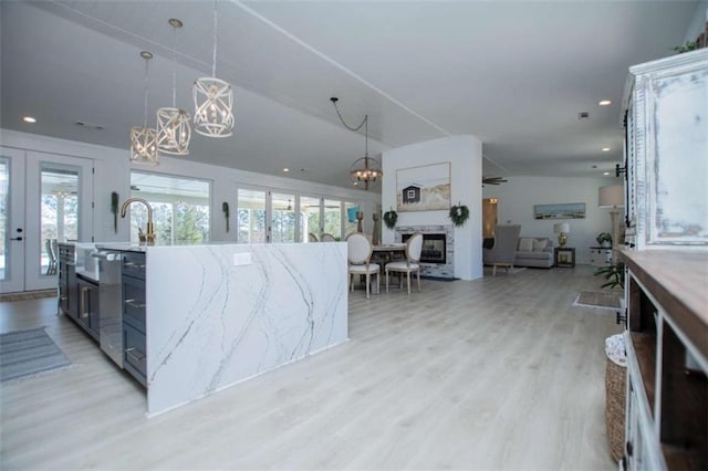 kitchen with french doors, plenty of natural light, light wood-style flooring, and an inviting chandelier