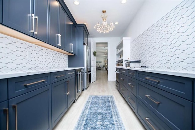 kitchen with light countertops, blue cabinetry, light wood-style flooring, and decorative backsplash