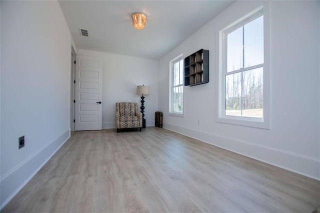 unfurnished room with wood finished floors, visible vents, and baseboards