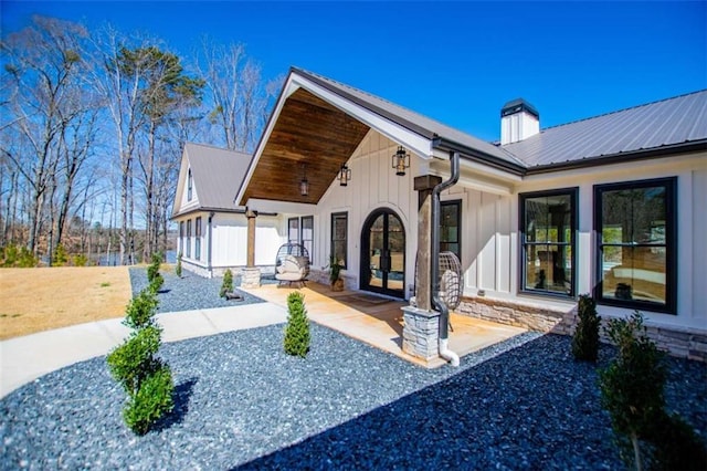 exterior space with stone siding, metal roof, board and batten siding, and french doors