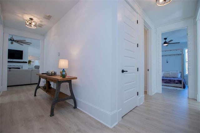 hallway featuring light wood-type flooring, visible vents, and baseboards