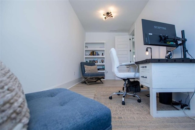 home office with built in features, baseboards, and wood finished floors